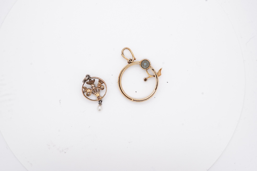 An early 20th century yellow metal, diamond chip and seed pearl set drop pendant, overall 23mm, together with a similar yellow metal, diamond and gem set open work pendant, diameter 20mm, gross weight 3.7 grams. Conditio